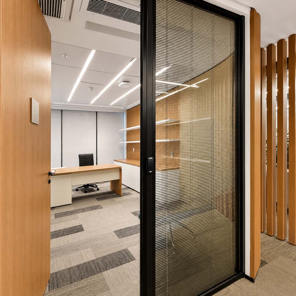 Demountable glass wall partition with integrated blinds and wood finishes in a modern office interior