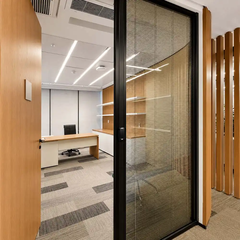 Demountable glass wall partition with integrated blinds and wood finishes in a modern office interior