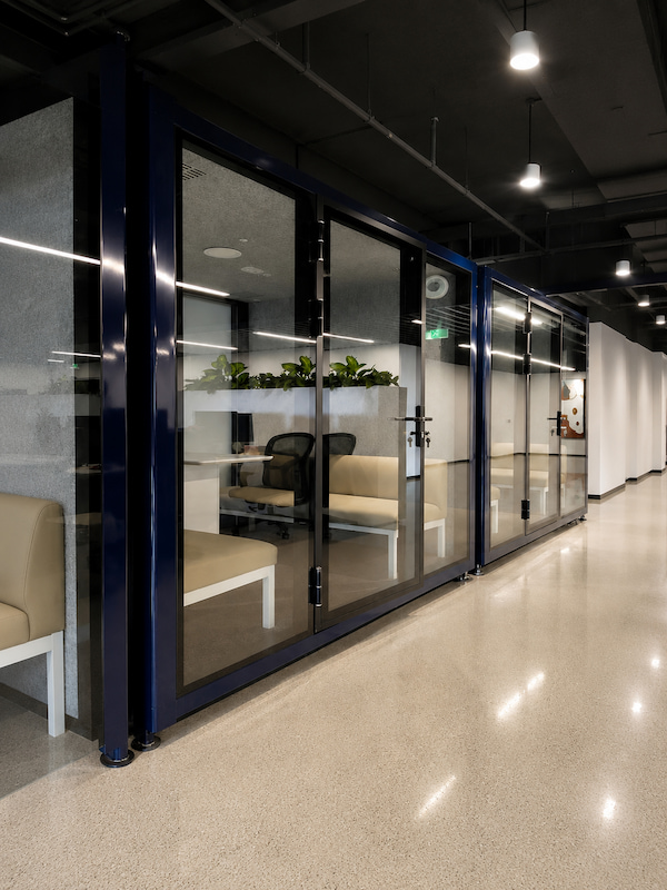 dark blue glass front office pods with bench seating installed along an office corridor in shenzhen