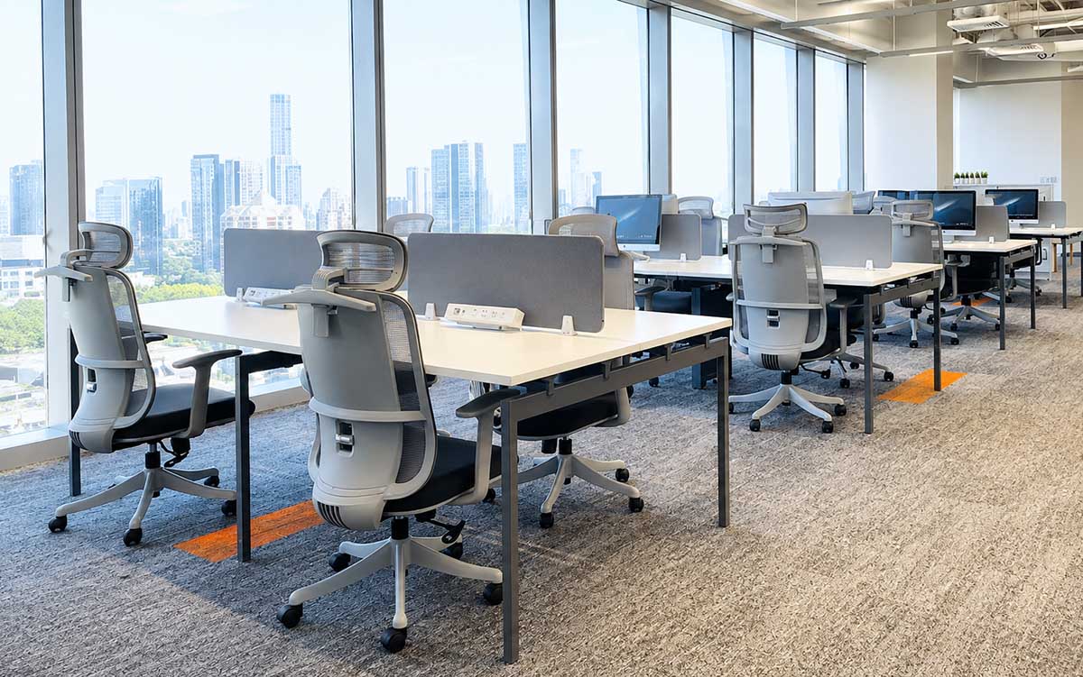 Open-plan office with benching workstations, desk screens, and office chairs