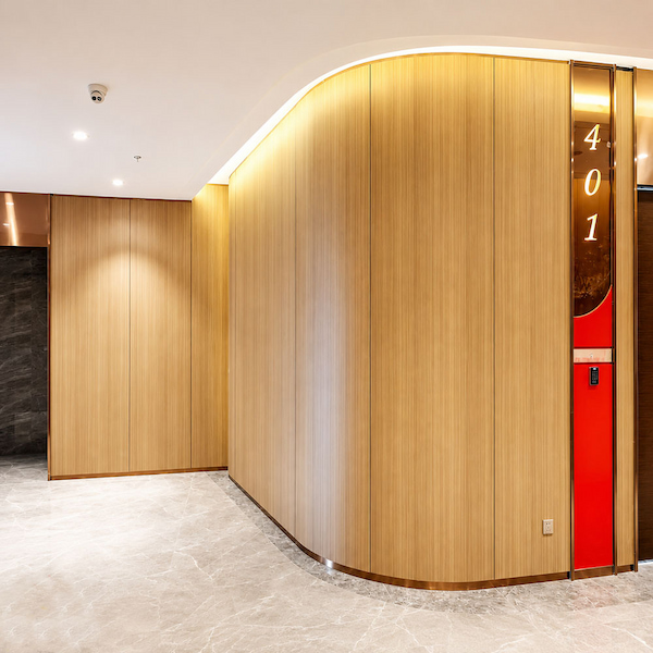 curved wood finish wall forming an enclosed corridor beside an elevator entrance