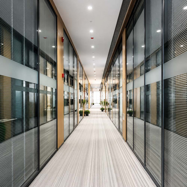 office corridor lined with full height framed glass partitions and integrated blinds