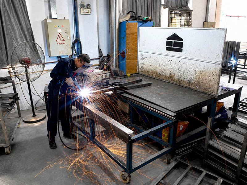 worker welding metal components during height adjustable desk frame production