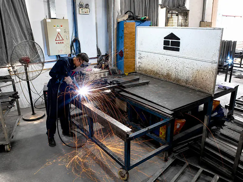 worker welding metal components during height adjustable desk frame production