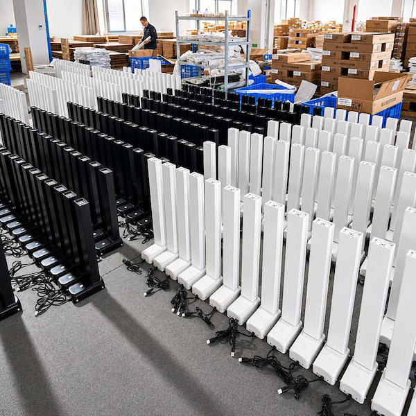 rows of black and white height adjustable desk lifting columns on a factory floor