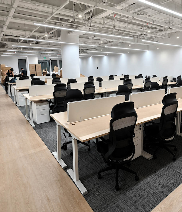 completed office with rows of height adjustable workstations privacy screens and task chairs