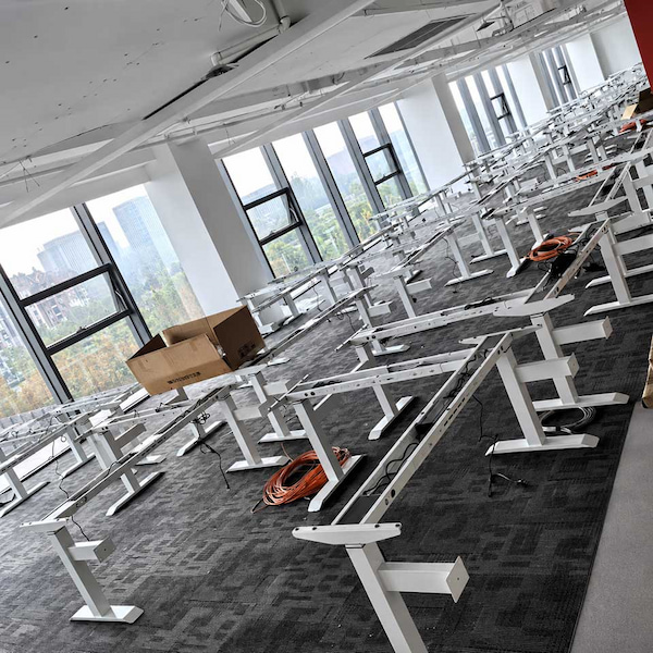 height adjustable desk frames and components arranged across an office floor before tabletop and electrical installation