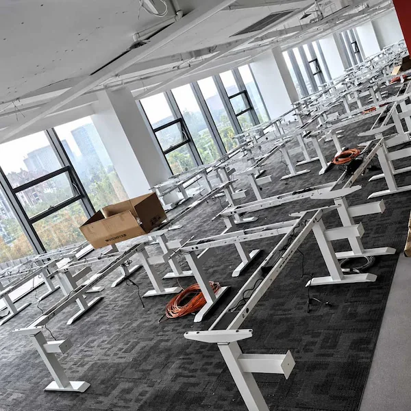 height adjustable desk frames and components arranged across an office floor before tabletop and electrical installation