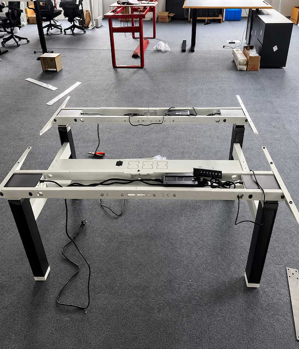 height adjustable desk frame with control box wiring and lifting columns exposed for replacement part identification