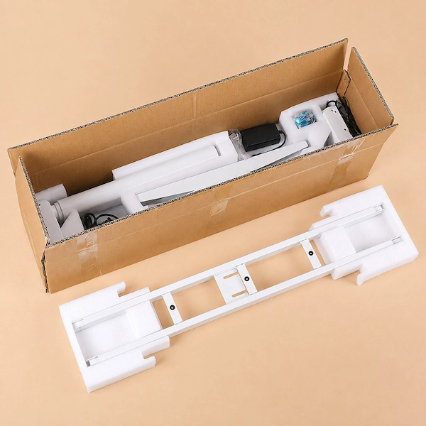white height adjustable desk frame and components packed in a cardboard carton with protective foam